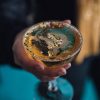 Hand holding glass of champagne sparkling wine glitter gold Flocos de ouro comestível 24K aplicados em cocktail